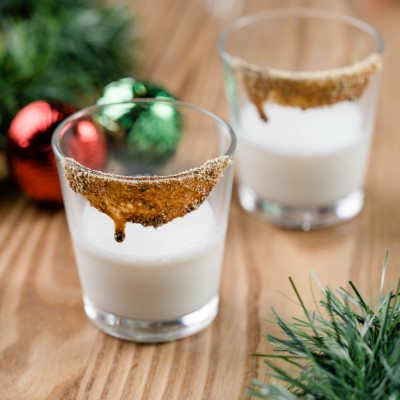 Two Shot Glasses with Eggnog and Sugar Rims with Christmas garland in the Background